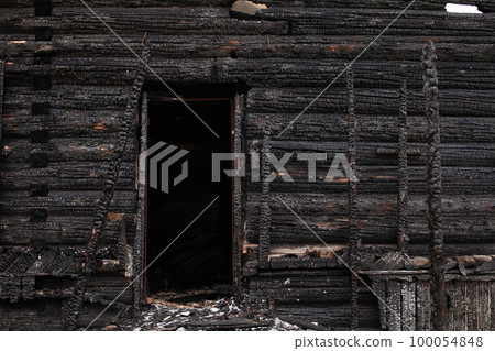Burned wooden house, black remains of construction 100054848