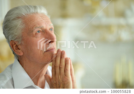 portrait of sad thinking senior man praying 100055828