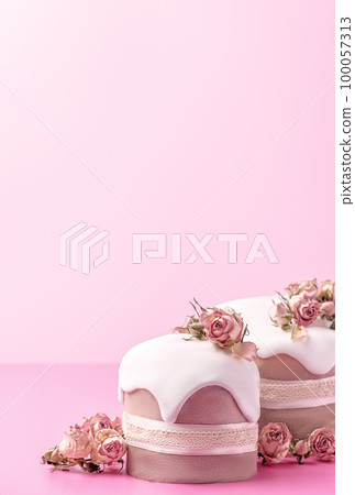 Glazed Easter cakes decorated with dry tea rose flowers on bright pink background. Easter composition with cakes, roses and chocolate eggs. Holiday background with copy space for your design. Glazed Easter cakes decorated with dry tea rose flowers on bright pink background. Easter composition with cakes, roses and chocolate eggs. Holiday background with copy space for your design. 100057313
