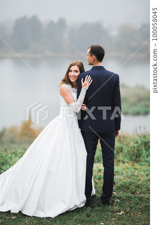 Beautiful romantic wedding couple of newlyweds hugging in park 100058045