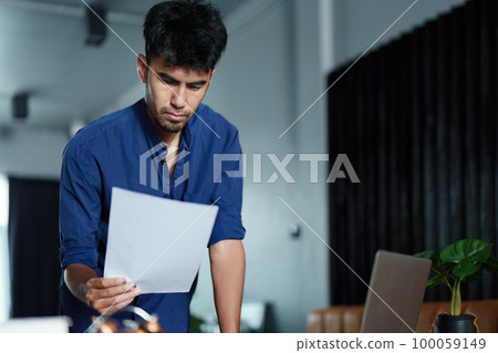 A portrait of a good-looking and discreet Asian man sitting at his desk with a thoughtful look on his computer. A portrait of a good-looking and discreet Asian man sitting at his desk with a thoughtful look on his computer. 100059149