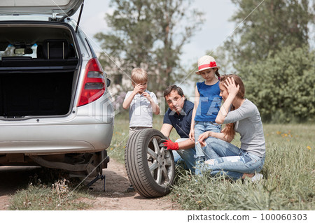 family with two children replace the tire of the family car. 100060303