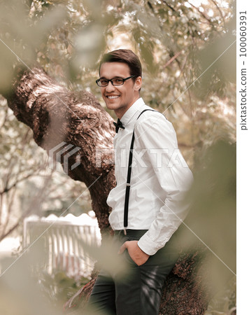 smiling groom standing among the trees in the spring garden. 100060391