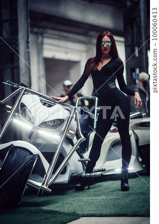 fashionable young woman standing near the steep custom trike 100060413