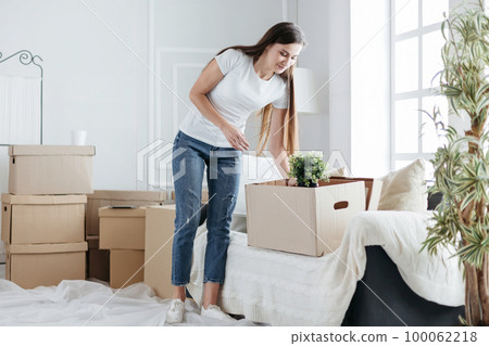 happy young woman takes things out of cardboard boxes 100062218