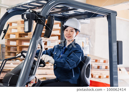 Female worker operating heavy machinery Female worker operating heavy machinery 100062414
