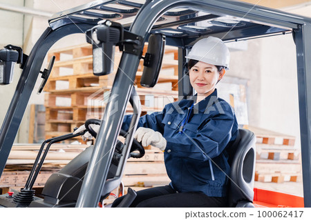 Female worker operating heavy machinery Female worker operating heavy machinery 100062417