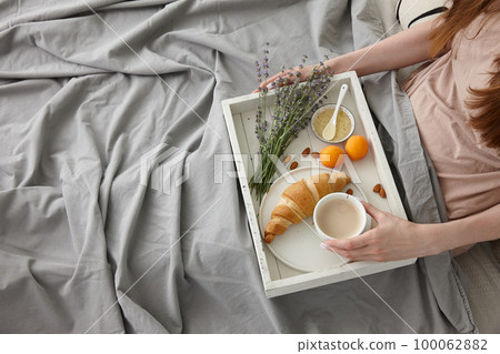 Woman having breakfast in bed in the morning Woman having breakfast in bed in the morning 100062882