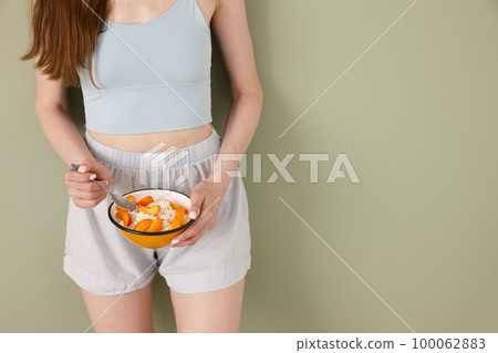 Young athletic woman with a bowl of healthy breakfast Young athletic woman with a bowl of healthy breakfast 100062883