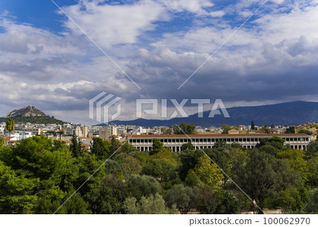 The Stoa of Attalos surrounded by hills covered in greenery under the cloudy sky in Greece 100062970