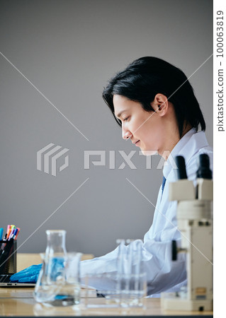 一位穿白大褂的年輕人將實驗數據輸入個人電腦 一位穿白大褂的年輕人將實驗數據輸入個人電腦 100063819