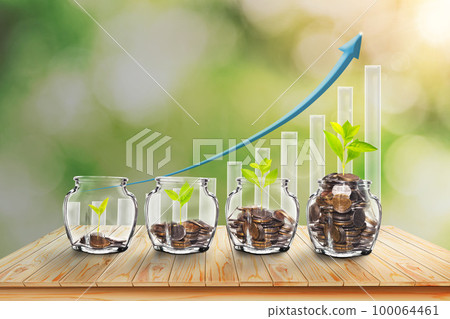 Growing Plants in Savings Coins - Investment and Interest Ideas. Money growing plant with fiery light effect - money growing concept.  with green blur nature background. 100064461