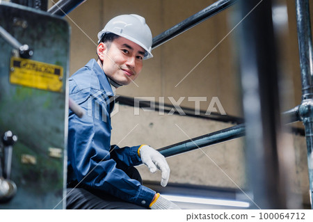 Male worker working at height on scaffolding 100064712