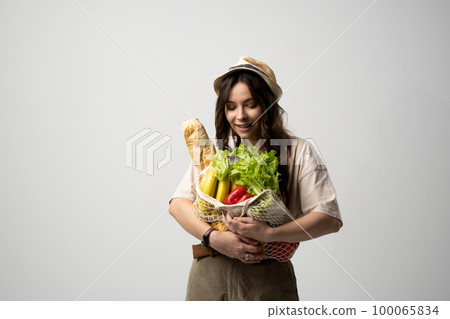 Zero waste concept. Young brunette woman holding reusable eco bag and shopping in zero waste plastic free store with reusable mesh bag. Low waste lifestyle. Sustainable eco lifestyle concept. Zero waste concept. Young brunette woman holding reusable eco bag and shopping in zero waste plastic free store with reusable mesh bag. Low waste lifestyle. Sustainable eco lifestyle concept. 100065834