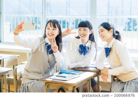A high school girl taking a selfie using a smartphone in the classroom A high school girl taking a selfie using a smartphone in the classroom 100066976