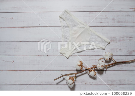 White lace underpants with cotton brunch on wooden background, closeup 100068229