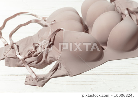 Set of Beige bra on wooden background, closeup. 100068243