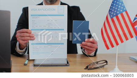 American consular officer showing visa application and passport, legal immigration, tourist interview. 100068803
