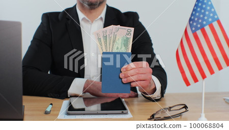American migrant officer holding passport with dollars, payment for id card services. 100068804