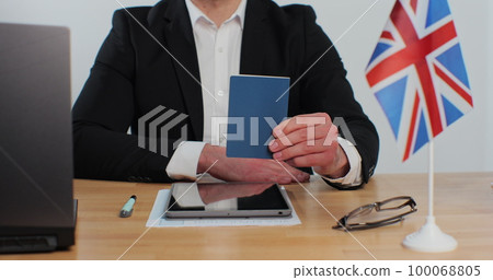British embassy man officer showing passport immigrant, work visa, citizenship. Visa Application online form immigration concept. Visa approval. 100068805
