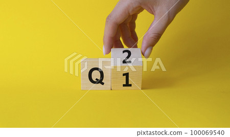 From 1st Quarter to 2nd symbol. Businessman hand Turnes cube and changes words 1st Quarter to 2nd Quarter. Beautiful yellow background. Business and Quarter concept. Copy space 100069540