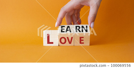 Learn and Love symbol. Businessman hand turns wooden cubes and changes word Love to Learn. Beautiful orange background. Lifestyle and Learn and Love concept. Copy space. 100069556