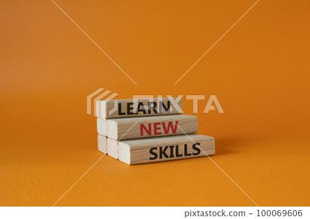 Learn new skills symbol. Concept words Learn new skills on wooden blocks. Beautiful orange background. Business and Learn new skills concept. Copy space. 100069606
