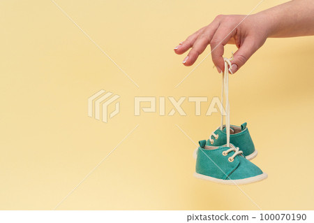 Female hand holding newborn baby shoes with laces Female hand holding newborn baby shoes with laces 100070190