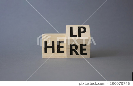 Help is here symbol. Turned wooden cube with words Here to Help. Beautiful grey background. Business and Help is here concept. Copy space 100070746