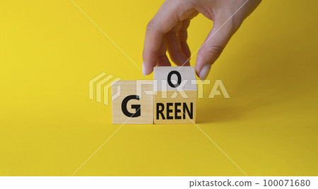 Go green symbol. Businessman hand Turnes cubes with words Go Green. Beautiful yellow background. Ecological and Business and Go green concept. Copy space 100071680
