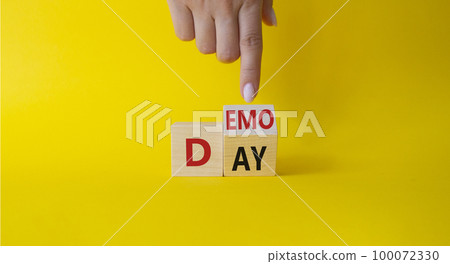 Demo Day symbol. Businessman hand points at turned wooden cubes with concept words Demo Day. Beautiful yellow background. Business and Demo day concept. Copy space 100072330