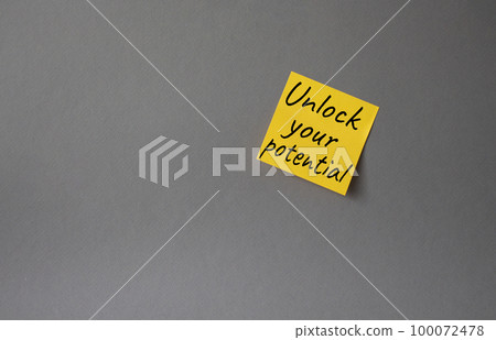 Unlock your Potential symbol. Concept words Unlock your Potential on orange steaky note. Beautiful grey background. Business and Unlock your Potential concept. Copy space. 100072478