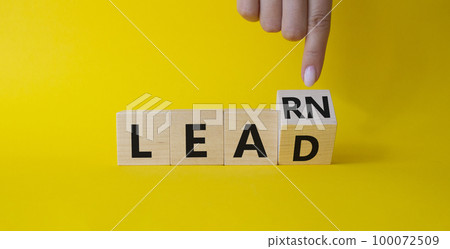 Learn and Lead symbol. Businessman hand points at turned wooden cubes with words Learn and Lead. Beautiful yellow background. Business and Learn and Lead concept. Copy space 100072509