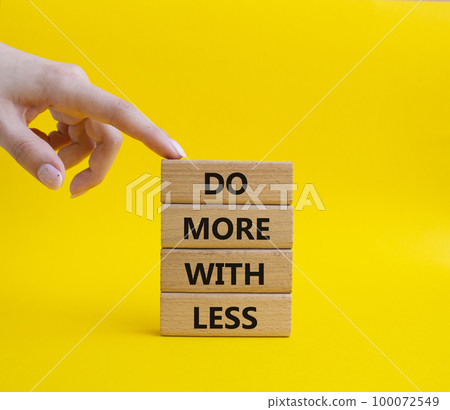 Do more with less symbol. Concept words Do more with less on wooden blocks. Beautiful yellow background. Businessman hand. Business and Do more with less concept. Copy space. Do more with less symbol. Concept words Do more with less on wooden blocks. Beautiful yellow background. Businessman hand. Business and Do more with less concept. Copy space. 100072549
