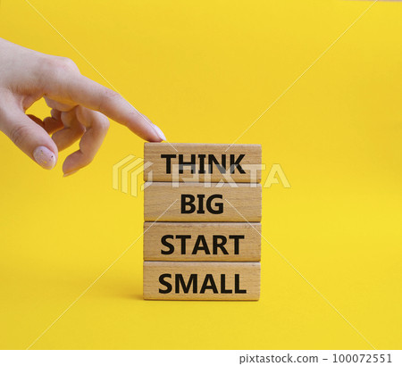 Think big start small symbol. Concept words Think big start small on wooden blocks. Beautiful yellow background. Businessman hand. Business and Think big start small concept. Copy space 100072551