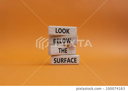 Look below the surface symbol. Concept word Look below the surface on wooden blocks. Beautiful orange background. Business and Look below the surface concept. Copy space 100074163