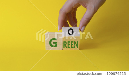 Go green symbol. Businessman hand Turnes cubes with words Go Green. Beautiful yellow background. Ecological and Business and Go green concept. Copy space 100074213
