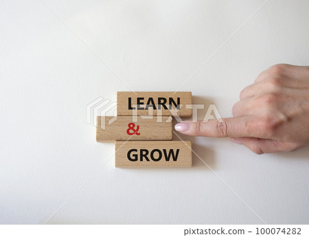 Learn and grow symbol. Concept words 'Learn and grow' on wooden blocks. Beautiful white background. Businessman hand. Business and Learn and grow concept. Copy space. 100074282