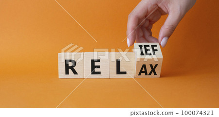 Relief and relax symbol. Hand turns cubes and changes the word Relief to Relax. Beautiful orange background. Businessman hand. Business and Relief and relax concept. Copy space Relief and relax symbol. Hand turns cubes and changes the word Relief to Relax. Beautiful orange background. Businessman hand. Business and Relief and relax concept. Copy space 100074321