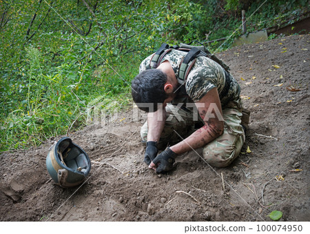 Sad soldier sits on the ground 100074950