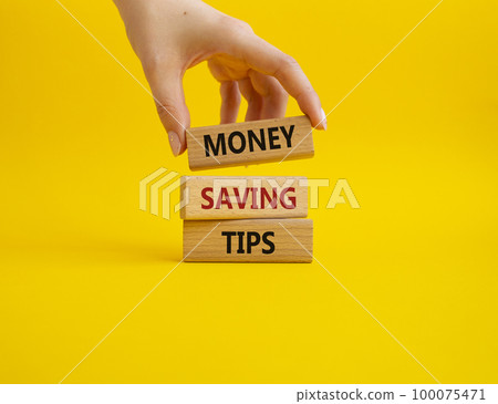 Money saving tips symbol. Concept words Money saving tips on wooden blocks. Beautiful yellow background. Businessman hand. Business and Money saving tips concept. Copy space. 100075471