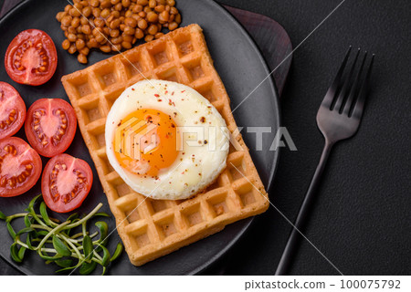 Delicious hearty breakfast consisting of a fried egg, Belgian waffle 100075792