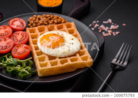 Delicious hearty breakfast consisting of a fried egg, Belgian waffle 100075793