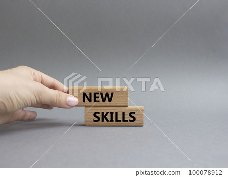 New skills symbol. Wooden blocks with words New skills. Beautiful grey background. Businessman hand. Business and New skills concept. Copy space. 100078912