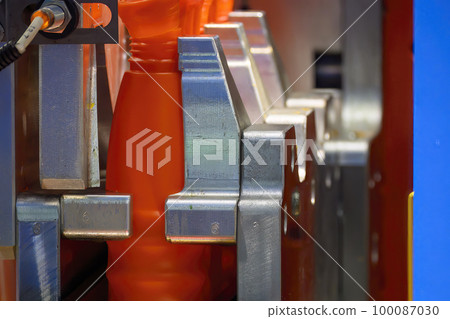 Close up scene the orange plastic bottle container manufacturing process by blow mold machine. Close up scene the orange plastic bottle container manufacturing process by blow mold machine. 100087030