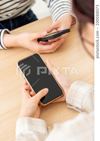 Young woman's hand holding a smartphone 100088073