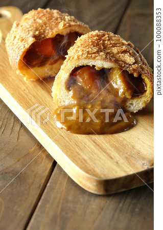 Hot curry bread cut in half on a cutting board with roux flowing out Hot curry bread cut in half on a cutting board with roux flowing out 100088353