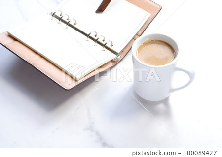 Desk work with coffee with milk and a system notebook Desk work with coffee with milk and a system notebook 100089427