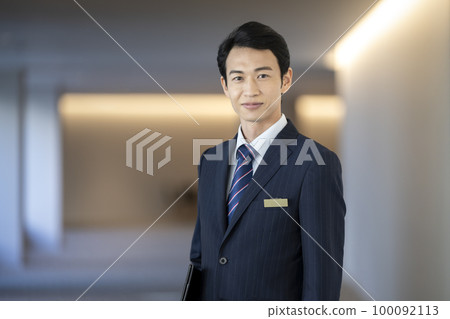 30 多歲的商人看著鏡頭前的禮賓部員工形象 100092113