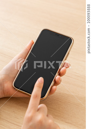 Young woman's hand holding a smartphone Young woman's hand holding a smartphone 100093888